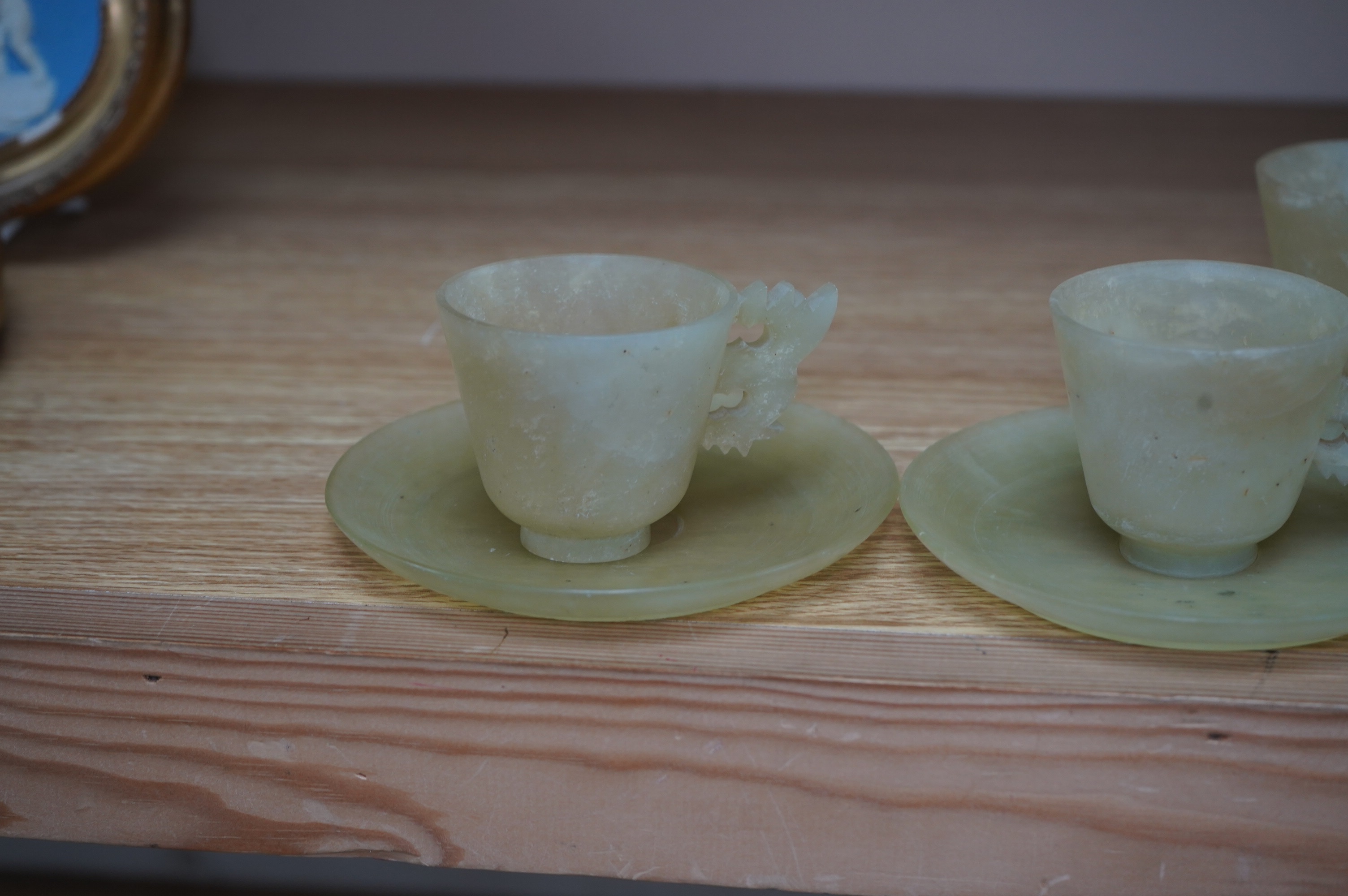 A set of seven Chinese bowenite jade cups and eight saucers, 11cm in diameter. Condition - fair to good